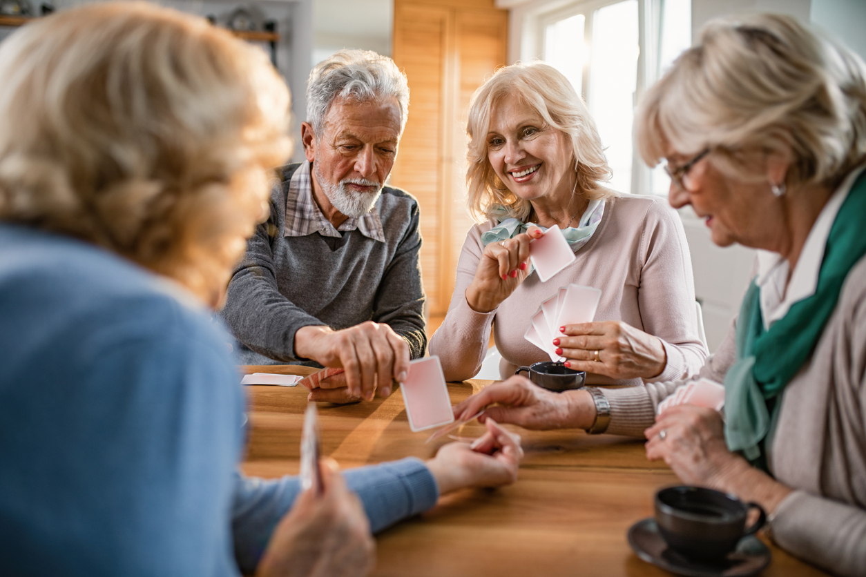 Small group of mature friends enjoying while playing cards at home. Happy seniors having fun while playing card game at home.