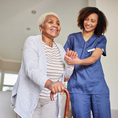 Supporting Steps: Caregiver and Senior Woman Warm scene of a caregiver assisting an elderly woman with a cane. Both are smiling, creating a heartwarming and supportive atmosphere indoors.